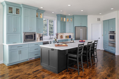 Inspiration for a mid-sized transitional l-shaped dark wood floor and brown floor eat-in kitchen remodel in Denver with an undermount sink, flat-panel cabinets, blue cabinets, quartzite countertops, white backsplash, glass tile backsplash, stainless steel appliances, an island and white countertops