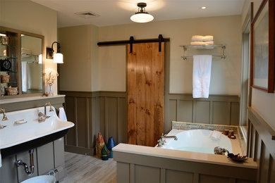 Eclectic bathroom in New York with a drop-in tub, multi-coloured tile, beige walls, light hardwood floors and a wall-mount sink.