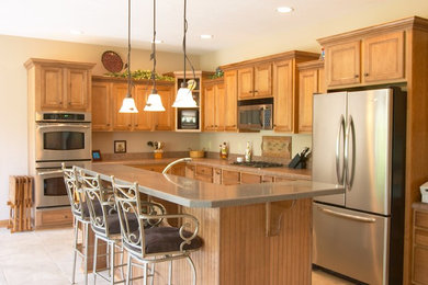 Eat-in kitchen - craftsman l-shaped ceramic tile eat-in kitchen idea in Indianapolis with an undermount sink, recessed-panel cabinets, light wood cabinets, solid surface countertops, stainless steel appliances and an island