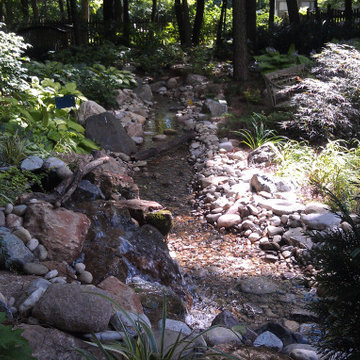 Shady Backyard with Waterfall, Stream, Fireplace and Landscape