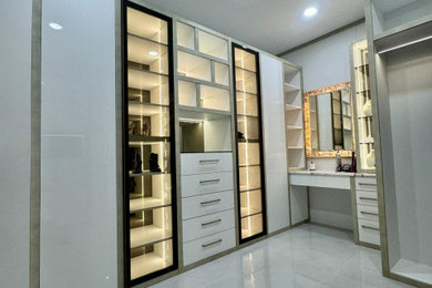 Modelo de armario vestidor unisex moderno grande con armarios tipo vitrina, puertas de armario blancas, suelo de baldosas de porcelana y suelo blanco