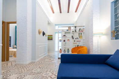 Foto de sala de estar abierta y blanca mediterránea de tamaño medio con paredes blancas, suelo de baldosas de cerámica, televisor colgado en la pared, suelo multicolor y vigas vistas