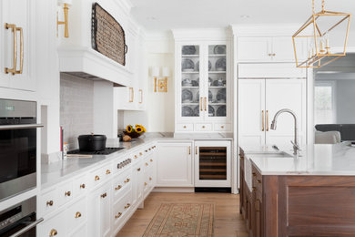 Large transitional l-shaped light wood floor and gray floor kitchen photo in Philadelphia with a farmhouse sink, shaker cabinets, white cabinets, quartz countertops, gray backsplash, ceramic backsplash, stainless steel appliances, an island and white countertops