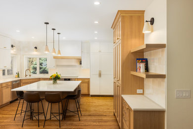 Eat-in kitchen - large transitional u-shaped medium tone wood floor and brown floor eat-in kitchen idea in Denver with an undermount sink, shaker cabinets, light wood cabinets, wood countertops, white backsplash, ceramic backsplash, paneled appliances, an island and beige countertops