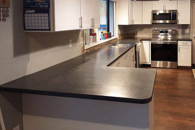 Kitchen - galley brown floor kitchen idea in Other with an undermount sink, shaker cabinets, white cabinets, solid surface countertops, stainless steel appliances, no island and black countertops