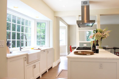 Eat-in kitchen - large transitional u-shaped light wood floor eat-in kitchen idea in New York with a farmhouse sink, shaker cabinets, white cabinets, marble countertops, stainless steel appliances and an island