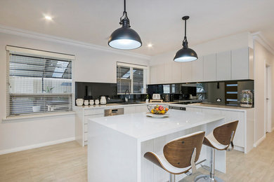 Inspiration for a mid-sized contemporary l-shaped eat-in kitchen in Adelaide with a double-bowl sink, flat-panel cabinets, white cabinets, granite benchtops, black splashback, glass sheet splashback, stainless steel appliances, light hardwood floors and with island.