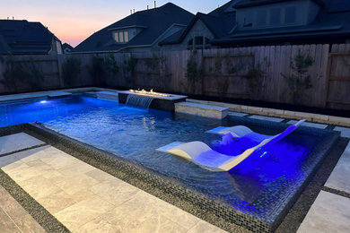 Modern l-shaped swimming pool in Houston with natural stone paving.