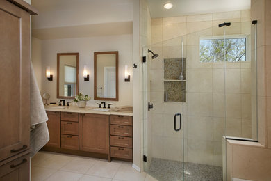 Photo of a transitional master bathroom in Phoenix with recessed-panel cabinets, medium wood cabinets, solid surface benchtops, a drop-in tub, a curbless shower, beige tile, stone tile and limestone floors.