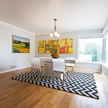 Dining room with bamboo flooring, light blue walls, a chevron rug, and contempor