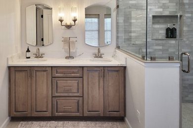 Mid-sized transitional master gray tile ceramic tile, beige floor and double-sink corner shower photo in New York with raised-panel cabinets, medium tone wood cabinets, white walls, an undermount sink, quartzite countertops, a hinged shower door, white countertops and a built-in vanity