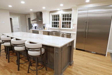 Eat-in kitchen - mid-sized transitional single-wall light wood floor and yellow floor eat-in kitchen idea in Boston with a farmhouse sink, beaded inset cabinets, white cabinets, quartz countertops, gray backsplash, ceramic backsplash, stainless steel appliances, an island and white countertops