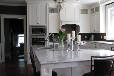 Inspiration for a large timeless u-shaped medium tone wood floor kitchen pantry remodel in Other with an undermount sink, recessed-panel cabinets, white cabinets, quartzite countertops, brown backsplash, stone tile backsplash, stainless steel appliances and an island