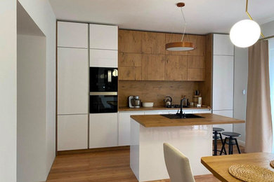 Идея дизайна: параллельная кухня среднего размера, в белых тонах с отделкой деревом в современном стиле с плоскими фасадами и островом