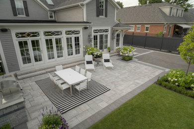 Large contemporary backyard garden in Toronto with natural stone pavers.