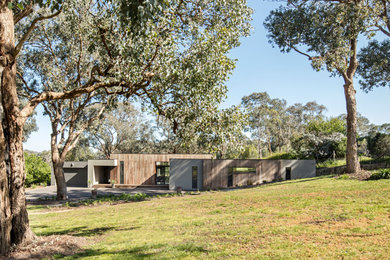 This is an example of a large contemporary one-storey house exterior in Melbourne with wood siding, a flat roof and a metal roof.