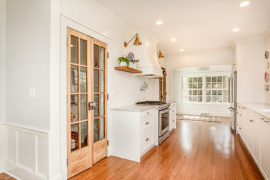 Inspiration for a timeless galley medium tone wood floor kitchen remodel in Chicago with shaker cabinets, white cabinets, marble countertops, white backsplash, ceramic backsplash and stainless steel appliances