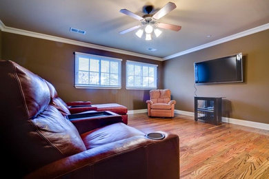 Inspiration for a large transitional enclosed medium tone wood floor and brown floor family room remodel in Other with brown walls, no fireplace and a wall-mounted tv