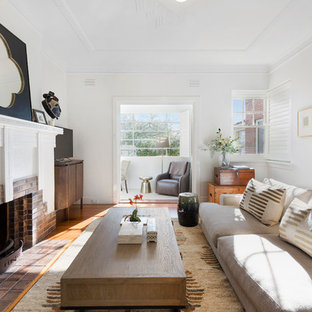 Design ideas for a mid-sized transitional family room in Melbourne with white walls, a standard fireplace, a brick fireplace surround, a freestanding tv and medium hardwood floors.