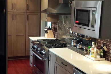 Enclosed kitchen - small contemporary galley medium tone wood floor and brown floor enclosed kitchen idea in Kansas City with shaker cabinets, gray cabinets, quartz countertops, gray backsplash, stone slab backsplash, stainless steel appliances, no island and white countertops
