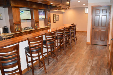 Large mountain style galley light wood floor seated home bar photo in Other with an undermount sink, raised-panel cabinets, medium tone wood cabinets, wood countertops and beige backsplash