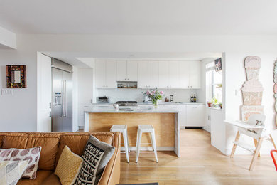 Kitchen - mid-sized contemporary u-shaped light wood floor and brown floor kitchen idea in New York with an undermount sink, shaker cabinets, white cabinets, quartzite countertops, stainless steel appliances, white backsplash and an island
