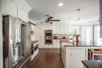 Inspiration for a mid-sized eclectic u-shaped bamboo floor enclosed kitchen remodel in Other with a farmhouse sink, recessed-panel cabinets, white cabinets, granite countertops, metallic backsplash, metal backsplash, stainless steel appliances and an island