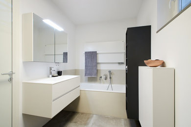 Mittelgroßes Modernes Duschbad mit flächenbündigen Schrankfronten, weißen Schränken, Einbaubadewanne, offener Dusche, Wandtoilette, weißer Wandfarbe, integriertem Waschbecken, Mineralwerkstoff-Waschtisch, grauem Boden, offener Dusche und weißer Waschtischplatte in Berlin