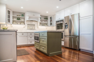 Example of a large trendy u-shaped medium tone wood floor eat-in kitchen design in San Francisco with a drop-in sink, shaker cabinets, white cabinets, marble countertops, white backsplash, ceramic backsplash, stainless steel appliances and an island