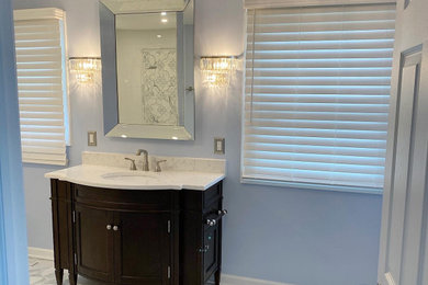 Photo of a large transitional master bathroom in Philadelphia with brown cabinets, an alcove shower, a two-piece toilet, white tile, ceramic tile, blue walls, porcelain floors, an undermount sink, engineered quartz benchtops, grey floor, white benchtops, a shower seat, a single vanity and a freestanding vanity.