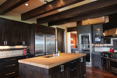 Example of a large trendy u-shaped medium tone wood floor and brown floor kitchen design in Denver with an undermount sink, shaker cabinets, dark wood cabinets, wood countertops, stainless steel appliances, an island, white backsplash and beige countertops