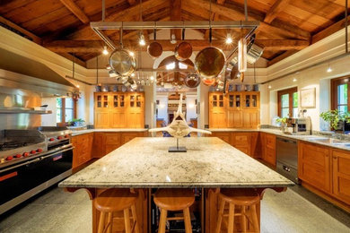 Photo of a large country u-shaped separate kitchen in Bridgeport with recessed-panel cabinets, medium wood cabinets, granite benchtops, limestone floors and with island.