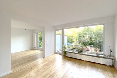 Mittelgroßes, Offenes Modernes Wohnzimmer mit hellem Holzboden, Kaminofen und weißer Wandfarbe in Düsseldorf