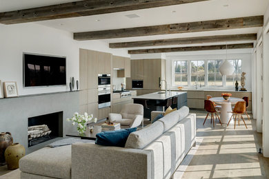 Inspiration for a contemporary open concept living room in New York with white walls, light hardwood floors, a ribbon fireplace, a concrete fireplace surround, a wall-mounted tv and beige floor.