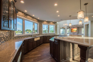 This is an example of an expansive beach style u-shaped eat-in kitchen in Tampa with an undermount sink, recessed-panel cabinets, grey cabinets, quartz benchtops, brown splashback, mosaic tile splashback, stainless steel appliances, with island and beige benchtop.