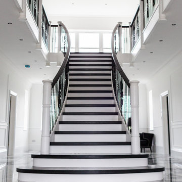 black and white curved staircase with wrought iron spindles