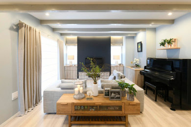 Imagen de salón abierto nórdico de tamaño medio con paredes azules, televisor colgado en la pared, suelo beige y papel pintado