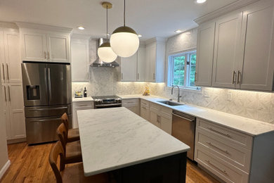 Inspiration for a mid-sized contemporary l-shaped light wood floor, brown floor and tray ceiling eat-in kitchen remodel in Other with an undermount sink, flat-panel cabinets, gray cabinets, quartzite countertops, white backsplash, marble backsplash, stainless steel appliances, an island and white countertops