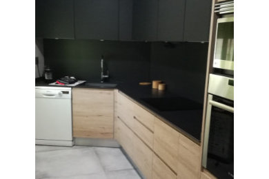 Foto de cocinas en L moderna de tamaño medio cerrada con fregadero bajoencimera, puertas de armario negras, encimera de azulejos, suelo de baldosas de porcelana, suelo gris y bandeja