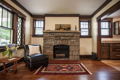 This is an example of an arts and crafts living room in Kansas City with medium hardwood floors, a standard fireplace and a stone fireplace surround.