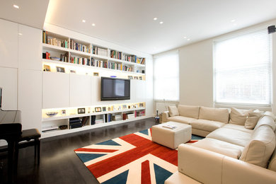 Photo of a contemporary family room in London with beige walls, dark hardwood floors, a wall-mounted tv and brown floor.