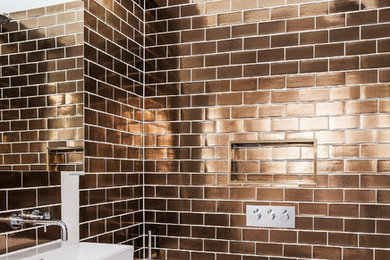 Inspiration for a contemporary bathroom in London with flat-panel cabinets, white cabinets, an alcove tub, a shower/bathtub combo, brown tile, subway tile and a console sink.