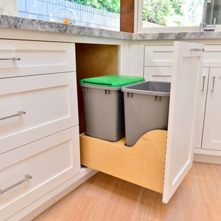 Cette image montre une arrière-cuisine design en U de taille moyenne avec un placard à porte shaker, des portes de placard blanches, un plan de travail en quartz, une crédence blanche, une crédence en carrelage de pierre, un électroménager en acier inoxydable, un sol en bois brun et aucun îlot.