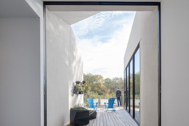 Imagen de terraza minimalista grande en patio delantero y anexo de casas con jardín de macetas, entablado y barandilla de metal