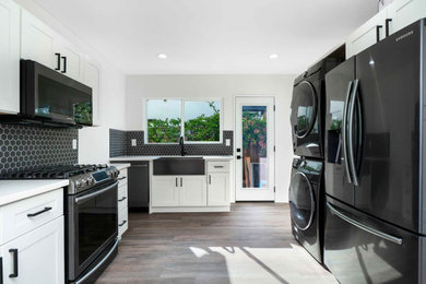 Elegant kitchen photo in Los Angeles with multicolored backsplash, ceramic backsplash, black appliances and white countertops