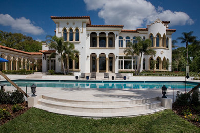 Inspiration for a large mediterranean white two-story stucco exterior home remodel in Orlando with a hip roof