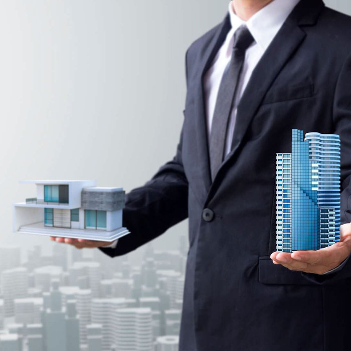 person holding two types of buildings of commercial development and residential development.