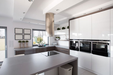 Mid-sized minimalist l-shaped porcelain tile and gray floor kitchen photo in Calgary with a double-bowl sink, flat-panel cabinets, white cabinets, concrete countertops, an island and gray countertops