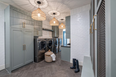 Example of a large trendy galley porcelain tile and gray floor utility room design in Dallas with an undermount sink, shaker cabinets, green cabinets, granite countertops, white backsplash, ceramic backsplash, white walls, a side-by-side washer/dryer and black countertops