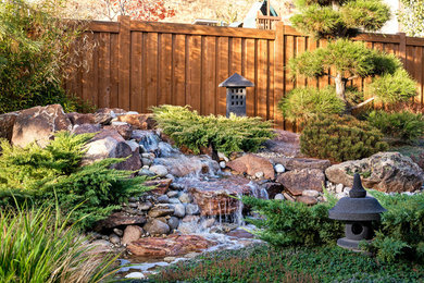 This is an example of a mid-sized asian backyard partial sun formal garden for summer in Boise with a water feature.
